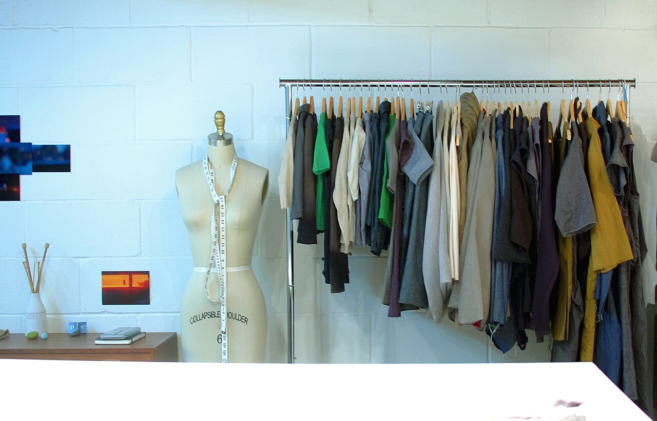 A dress form and a rail of clothing in a studio